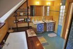 Podkrovní koupelna s keramickým obkladem teplých barev a dřevěným pódiem u vany potvrzuje příklon majitelů k přírodnímu stylu